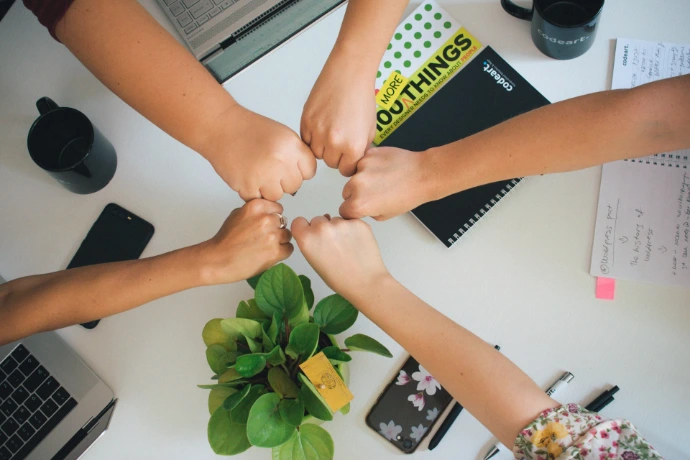 five fists bumping over office desk